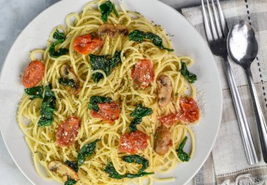 Sotelenmiş ıspanak ve domatesli peynirli spagetti üstü.