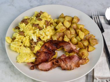 Sosisle karıştırılmış yumurta, domuz pastırması ve patates kızartması.,