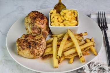 İki baharatlı tavuk budu yanında peynirli makarna ve patates kızartması.