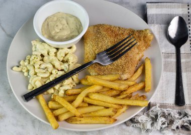 Patates kızartması ve makarna salatasıyla servis edilen mezgit balığı.