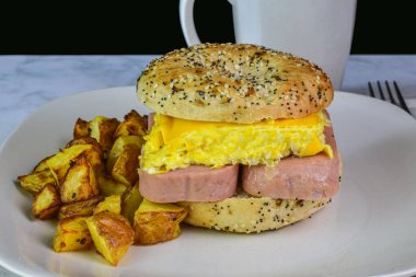 Kahvaltıda konserve jambon ve çırpılmış yumurtalı sandviç ve yanında patates kızartması., 