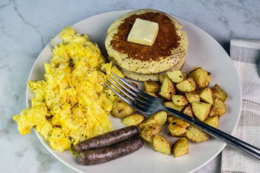 Üzerine biber ve sosis, patates kızartması ve krep ile servis edilen çırpılmış yumurta..