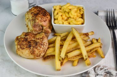 Baharatlı tavuk butları peynirli makarna ve patates kızartmasıyla servis edilir.