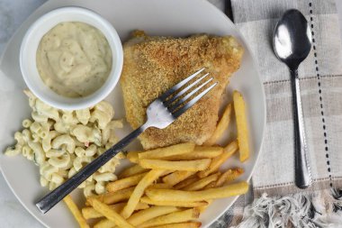 Makarna salatası ve patates kızartmasıyla servis edilen mezgit..