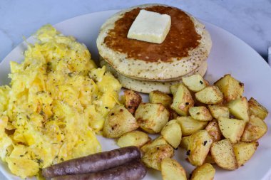 Üzerine biber ve sosis, patates kızartması ve krep ile servis edilen çırpılmış yumurta..
