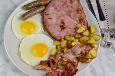 Domuz pastırmalı sahanda yumurta, sosis ve yanında patates kızartması.,