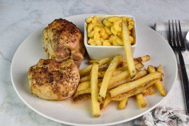 Baharatlı tavuk butları peynirli makarna ve patates kızartmasıyla servis edilir.