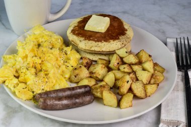 Üzerine biber ve sosis, patates kızartması ve krep ile servis edilen çırpılmış yumurta..