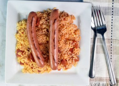 Doğranmış domatesle servis edilen iki sosisli., 