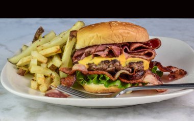 Biftek ve pastırmalı peynirli burger ve yanında patates kızartması.,.