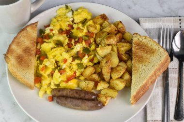 Kahvaltıda sosis ve patates kızartması ile servis edilen biberli omlet.