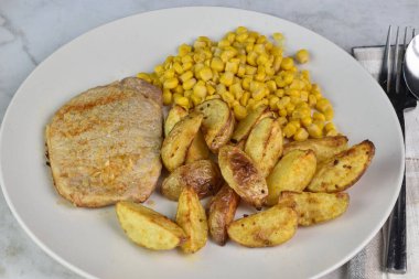 Soğanlı, sarımsaklı, patates dilimli ve mısırlı kemiksiz domuz pirzolası.,