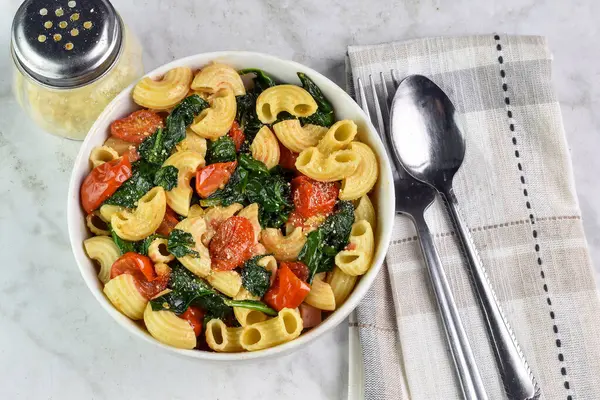 stock image elbow macaroni  served  with sauteed spiach and tomatoes