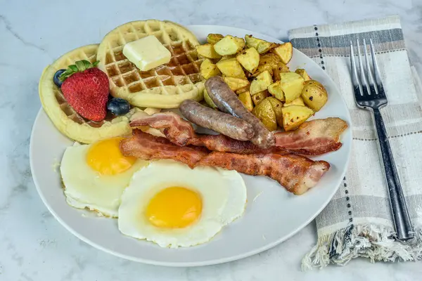 stock image fried eggs  with bacon and sausage served with  waffles and home fries