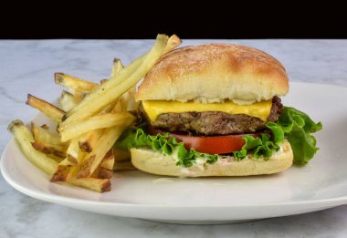 Peynirli burger, mayonez, marul ve domates kızarmış ekmekle servis edilir.