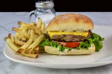 Peynirli burger, mayonez, marul ve domates brioche ekmeğinde servis edilir.