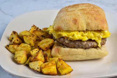 Patates kızartmasıyla servis edilen çöreğin arasında sosisli böreğin üstünde çırpılmış yumurta.