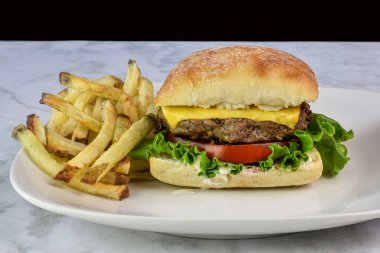 Peynirli burger, mayonez, marul ve domates kızarmış ekmekle servis edilir.