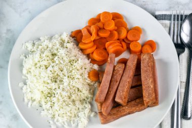 Maydanozlu beyaz pirinç üstü ve patates kızartması ve havuçla servis ediliyor..