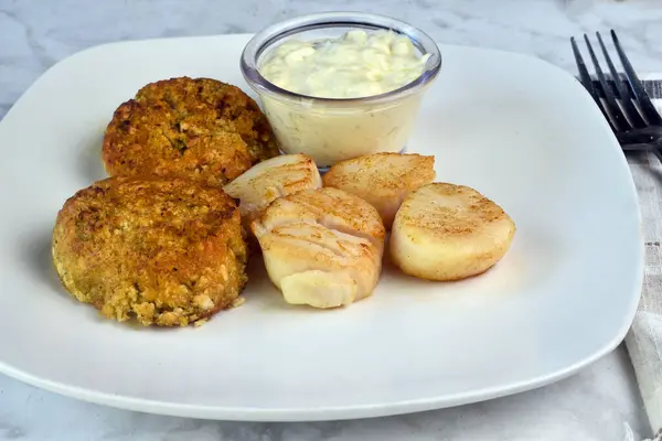 stock image  two crab cakes served with  sheared scallops with tarter sauce