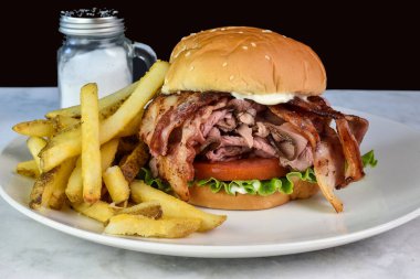 Patates kızartmasıyla servis edilen susamlı çöreğin arasında biftek kızartması.