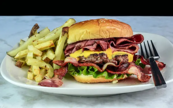 stock image cheese burger with  roastbeef and baco served with  french fries