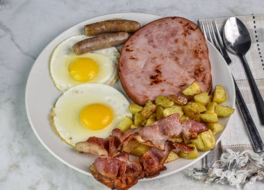 İki sahanda yumurta, sosis, jambon, yanında da patates kızartması..