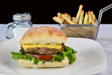 Peynirli burger, mayonez, marul ve domates kızarmış ekmekle servis edilir.