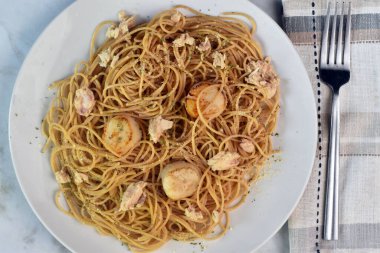 Maydanozlu buğday spagetti üstü ve istiridye ve ton balığıyla servis edilen parmesan peyniri.