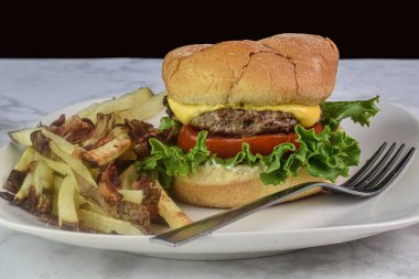 Peynirli burger, marul ve domatesli. Yanında da patates kızartması.