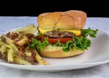 Peynirli burger, marul ve domatesli. Yanında da patates kızartması.