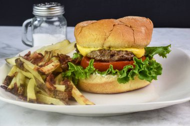 Peynirli burger, marul ve domatesli. Yanında da patates kızartması.