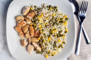  Mısır ve bezelyeli pilav, tavuk ısırığı ile servis edilir.