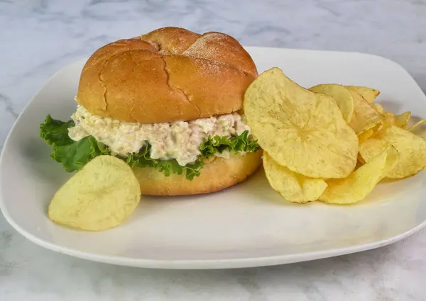 stock image chicken salad with lettuce served on a bulkie roll with  potato chips.