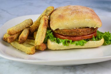 Vejetaryen burger, marul ve sebze kızartmasıyla servis edilen domates.