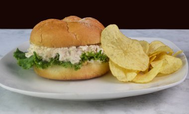 chicken salad salad  sandwich served witg a side of chips clipart