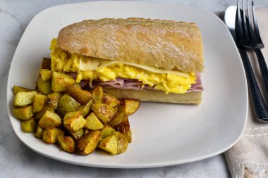 jambon, çırpılmış yumurta ve ciabatta sandviç ekmeğinde servis edilen İsviçre peyniri.,