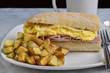 jambon, çırpılmış yumurta ve ciabatta sandviç ekmeğinde servis edilen İsviçre peyniri.,