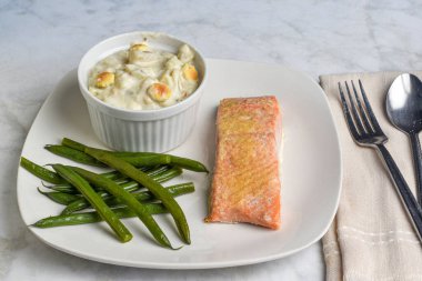 Fırında somon, deniz tarağı çorbası ve yeşil fasulye ile servis edilir.