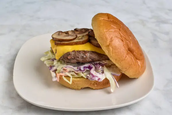 stock image cheese burger with  mushrooms  and cole slaw  served on a brioche bun