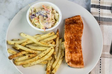 salmon covered in barbecue sauce  served with home made seasoned  french fries and cole slaw clipart