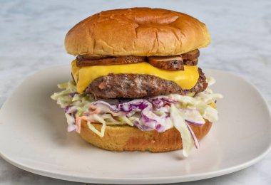 Peynirli burger ve mantarlı lahana salatası çörekte servis ediliyor.