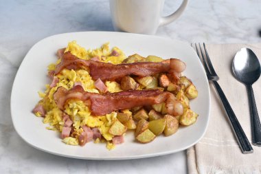 Domuz pastırması ve patates kızartması ile servis edilmiş jambonlu omlet.