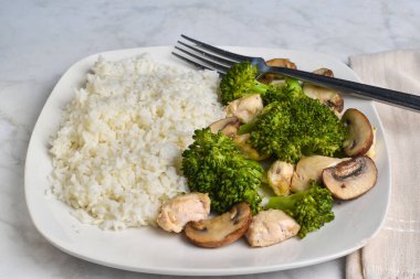 Buğulanmış brokoli ve sotelenmiş mantarla servis edilen beyaz pirinç.