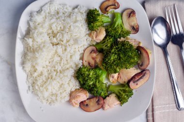 Buğulanmış brokoli ve sotelenmiş mantar ile beyaz pirinç servis edilir.