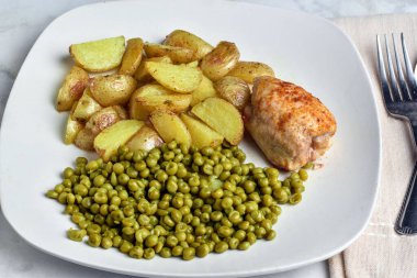  Mevsimlik pişmiş tavuk butları patates ve bezelye ile servis edilir.. 