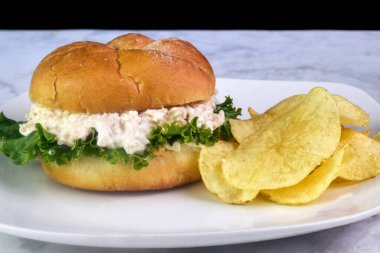 Tavuk salatalı sandviç yanında patates kızartması.