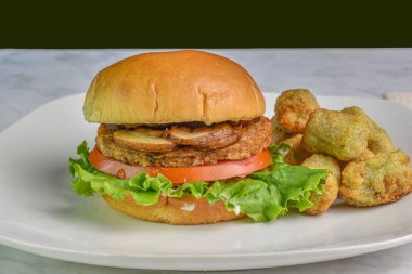 Mantarlı hamburger, domates ve brokoli kızartmasıyla servis edilen marul.