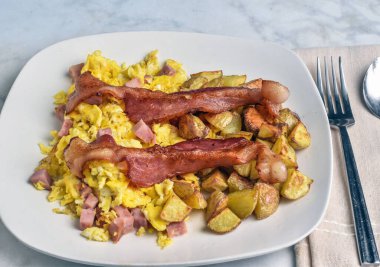 Domuz pastırması ve patates kızartması ile servis edilmiş jambonlu omlet.