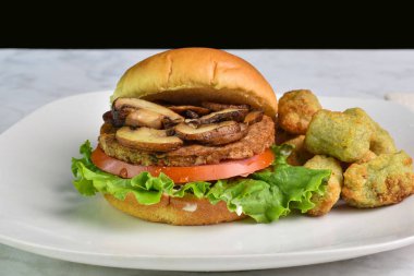 Mantarlı hamburger, domates ve brokoli kızartmasıyla servis edilen marul.